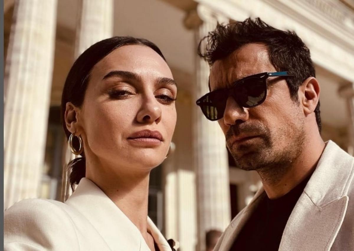 actrița poartă un palton alb și actor poartă un sacou alb și ochelari de soare