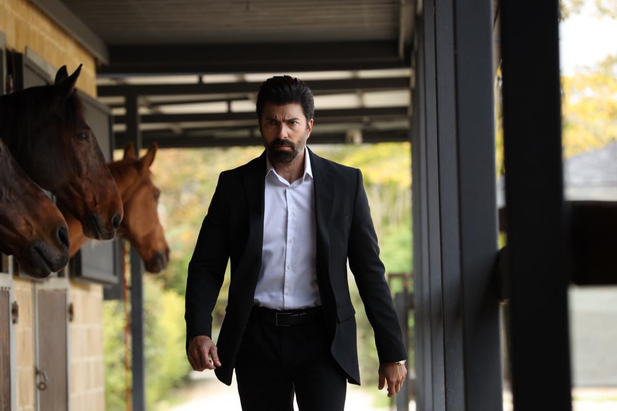 actor poartă costum și se află într-un grajd pentru cai