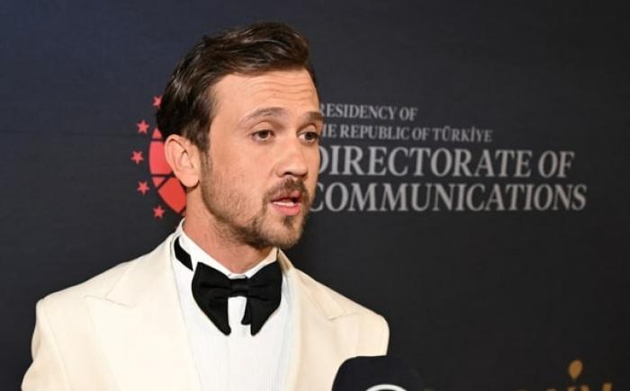 actorul poartă un costum alb și un papion negru