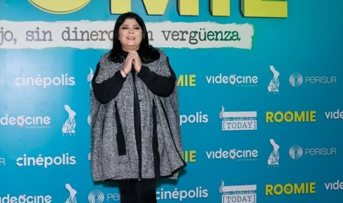 actrița poartă un poncho închis la culoare și zâmbește