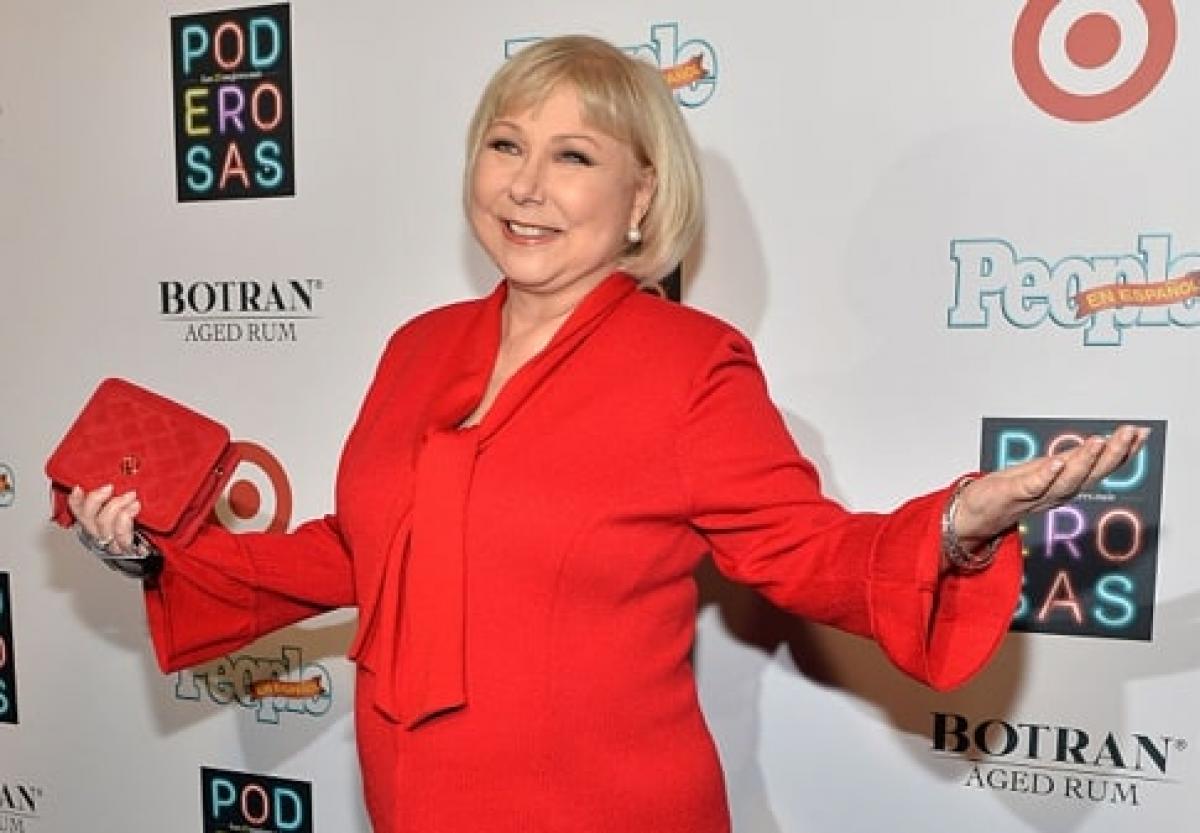 femeie poartă un costum roșu, are părul scurt, blond