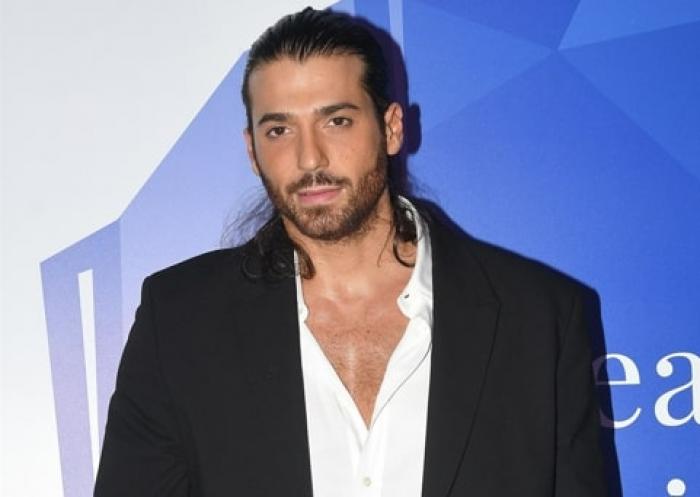 Can Yaman poartă o cămașă albă și sacou negru și păr prins în coadă la spate