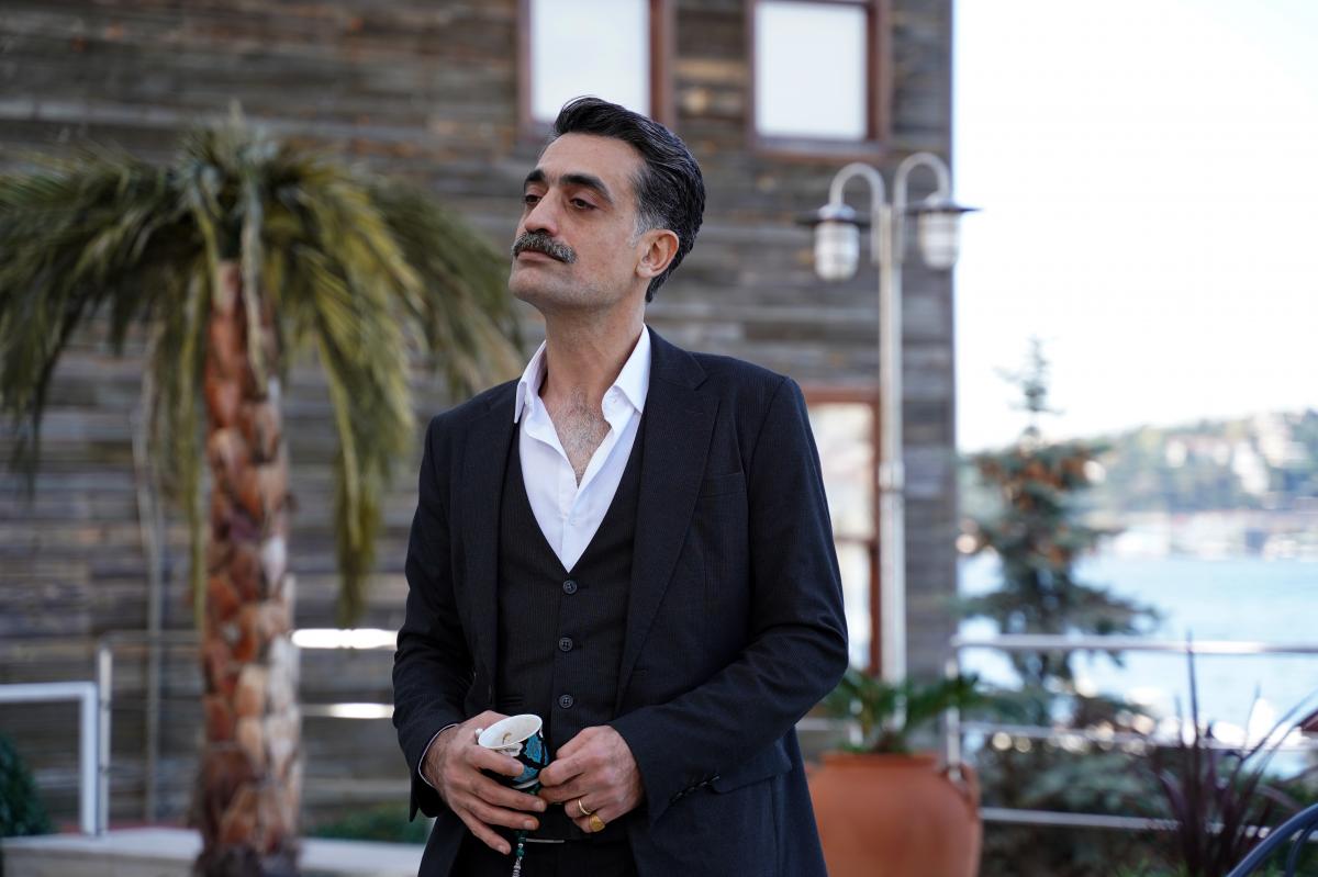 actor poartă cămașă albă și sacou negru