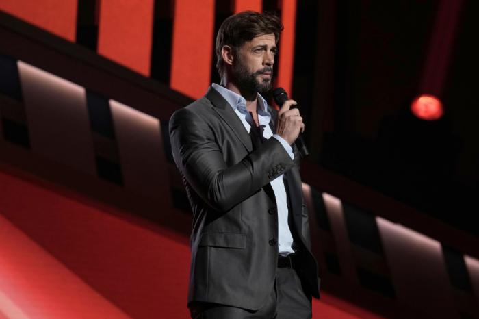 actor poartă un costum închis la culoare