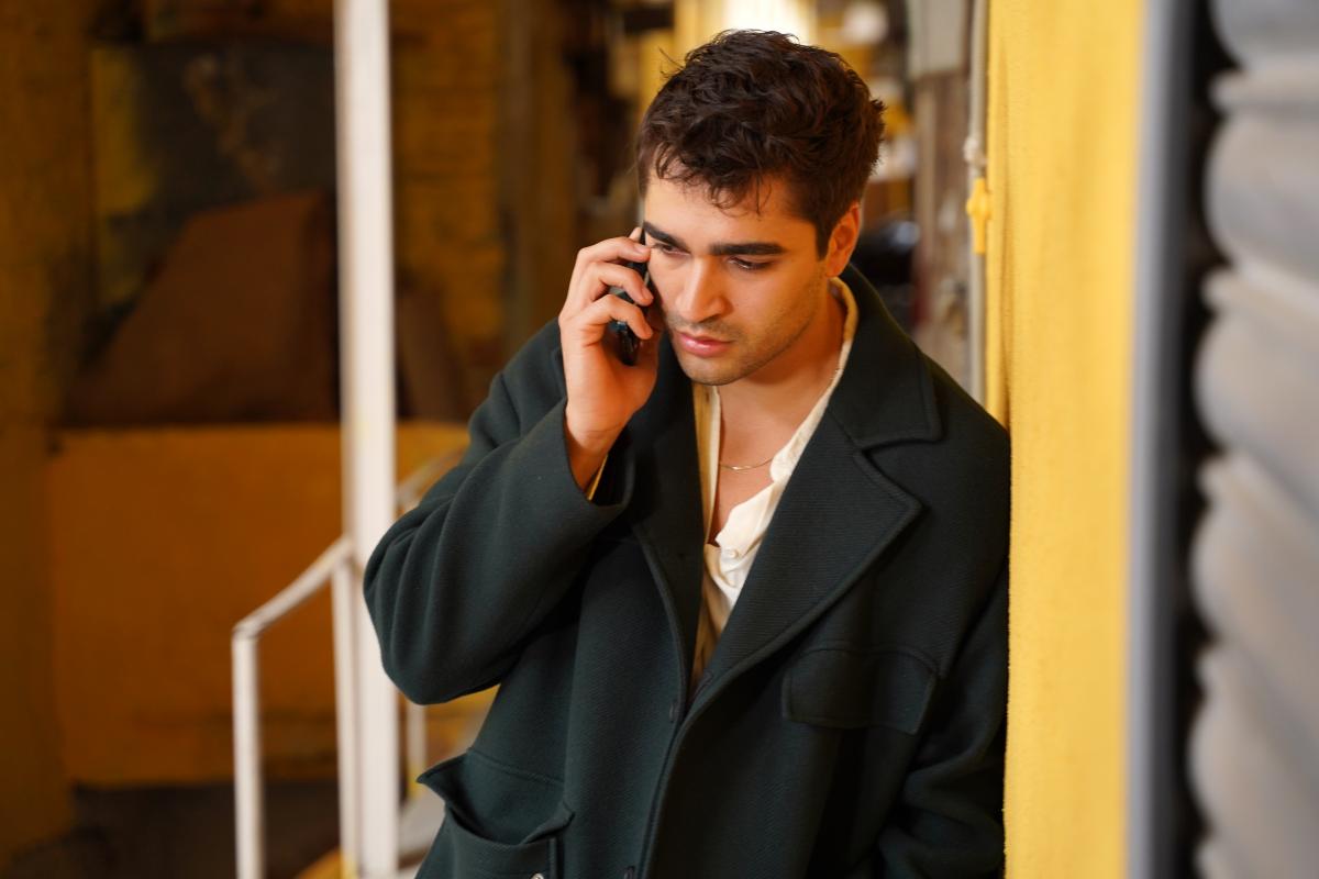 actor poartă un palton cu mâneci lungi și vorbește la telefon