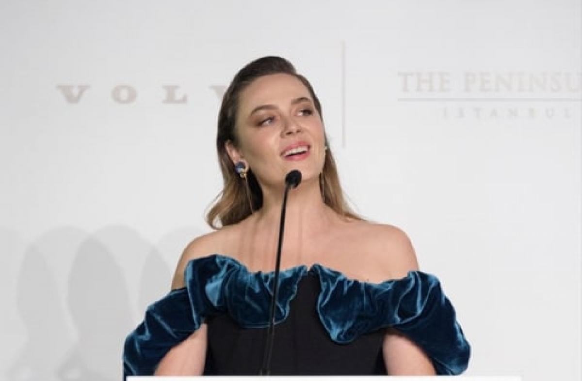 actrița stă în fața microfonului și poarte o rochie cu umerii goi