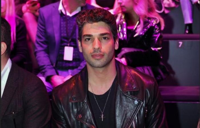 actor poartă ținută de culoare neagră pe un fundal mov