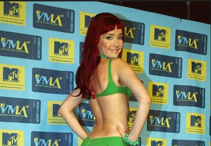 artista poartă părul roșcat și zâmbește