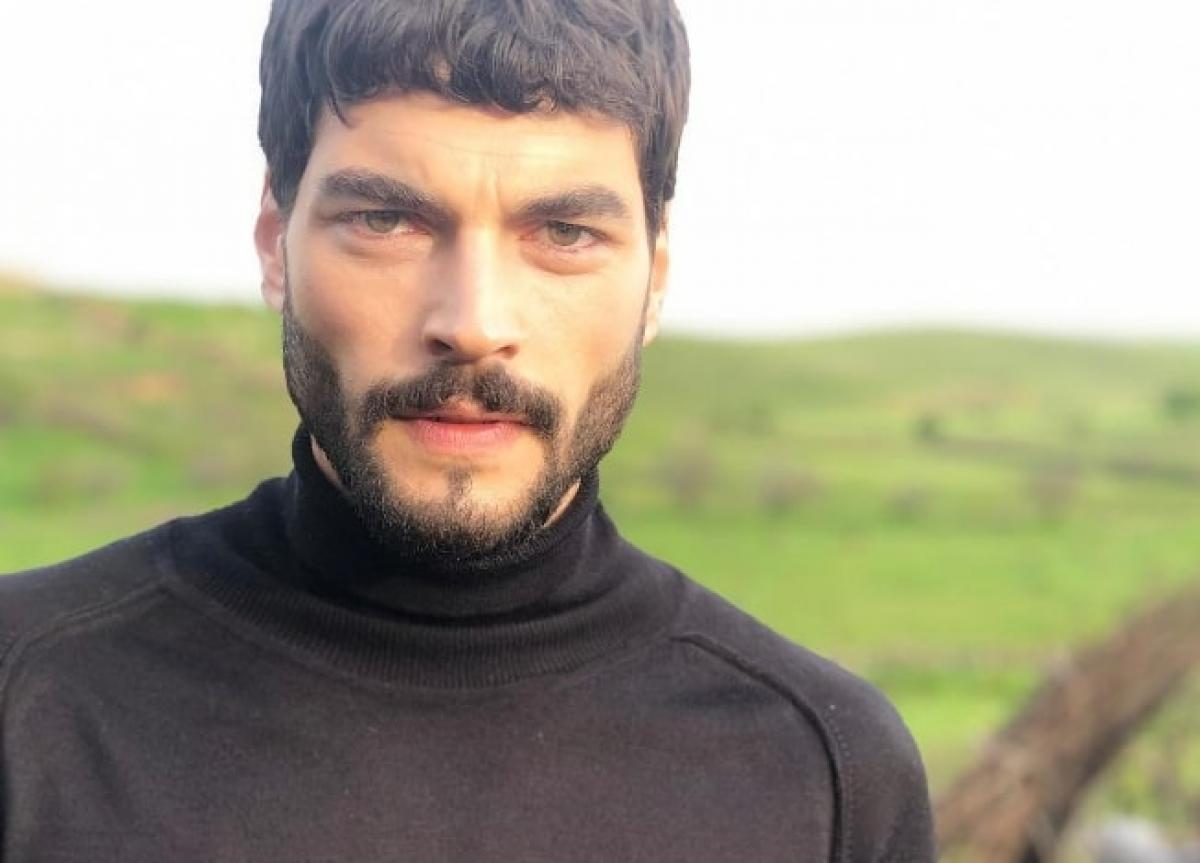 actor poartă o maletă neagră, pe gât