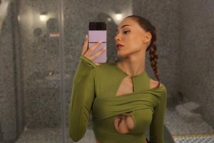 actrița poartă o bluză verde cu decolteu în timp ce își face o poză în oglindă