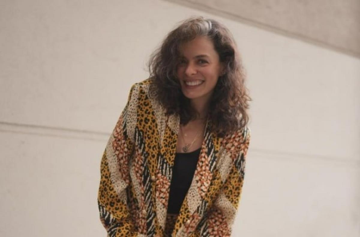 actrița poartă un costum și păr desprins și zâmbește