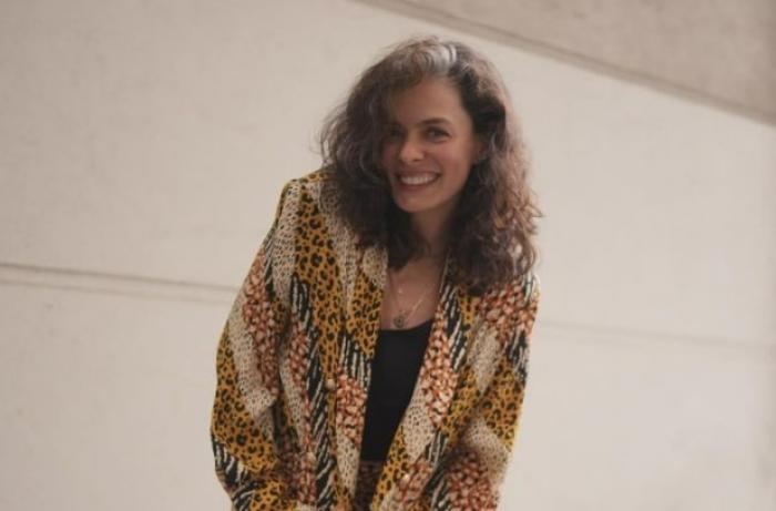 actrița poartă un costum și păr desprins și zâmbește