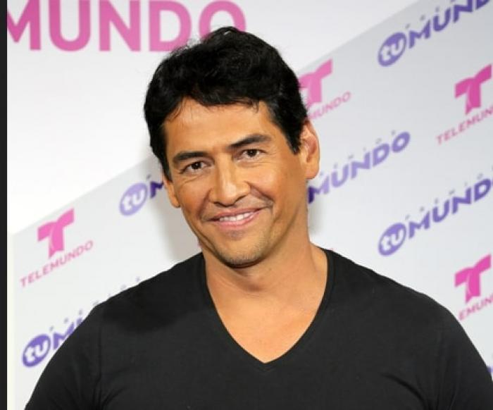 actor poartă un tricou negru și zâmbește