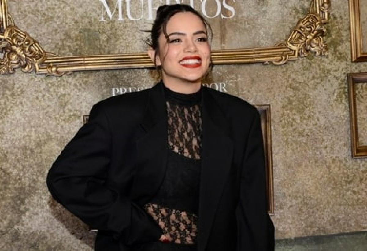 actrița poartă un body negru și un sacou aceeași culoare și zâmbește