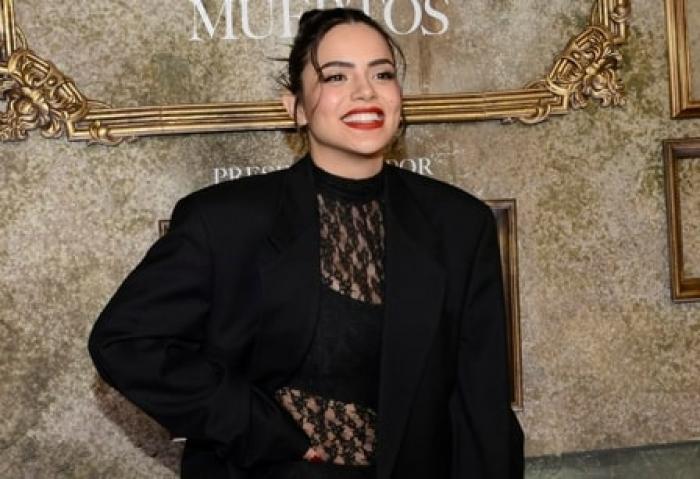 actrița poartă un body negru și un sacou aceeași culoare și zâmbește