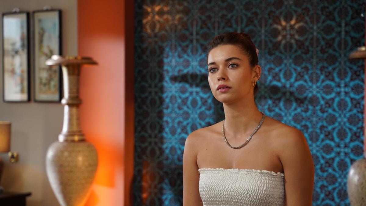 actriță poartă o rochie albă fără mâneci și părul prins în coc