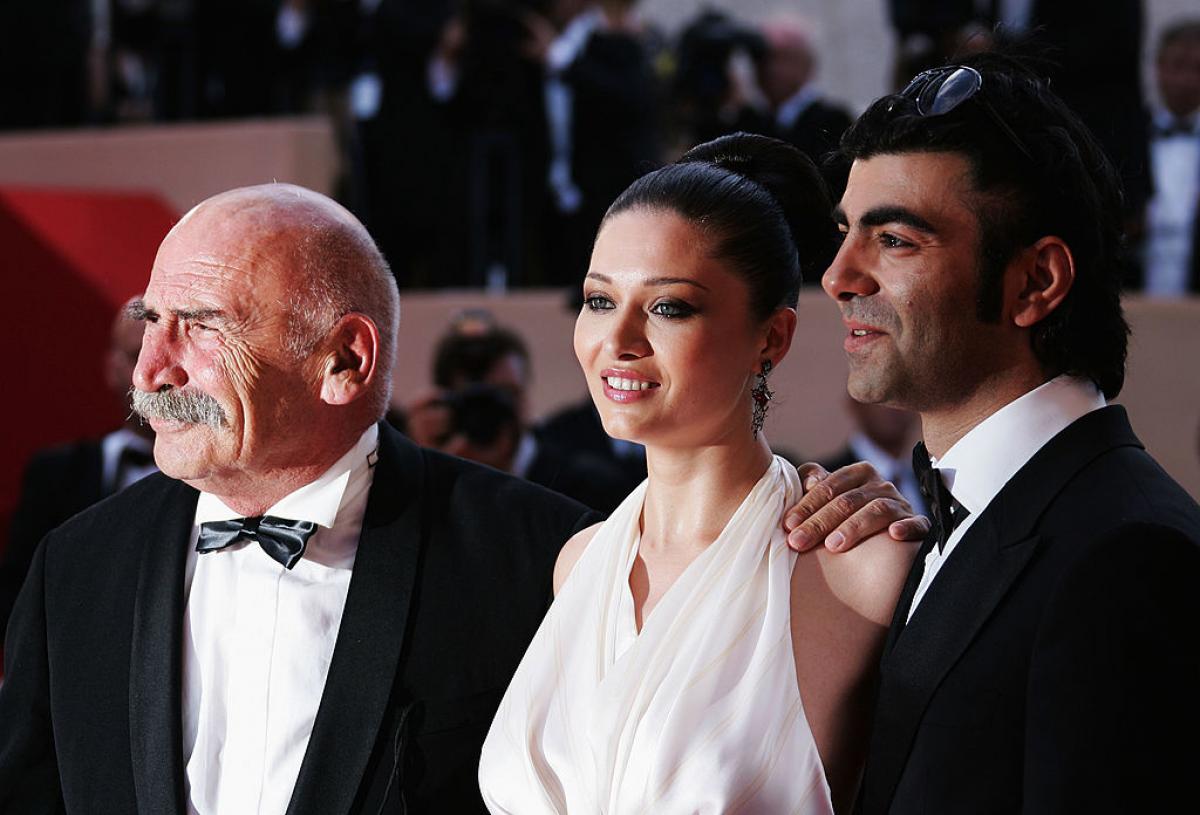 actrița poartă o rochie albă și stă între doi bărbați