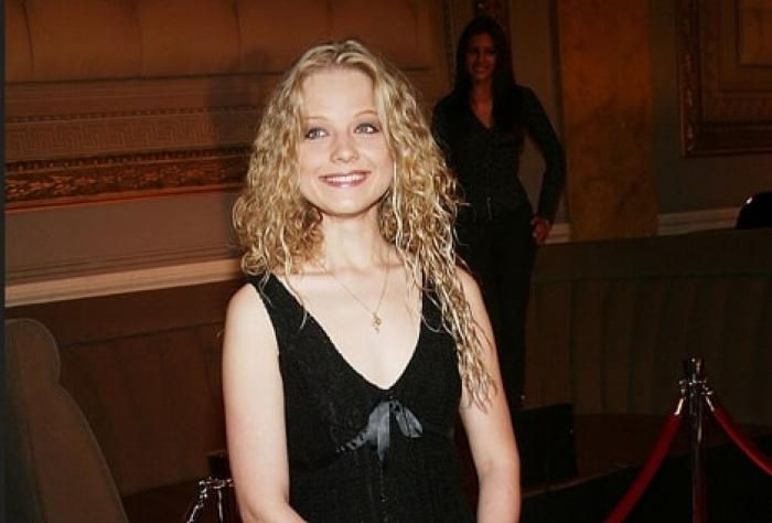 actriță poartă o rochie neagră fără mâneci, părul lung, blond și zâmbește