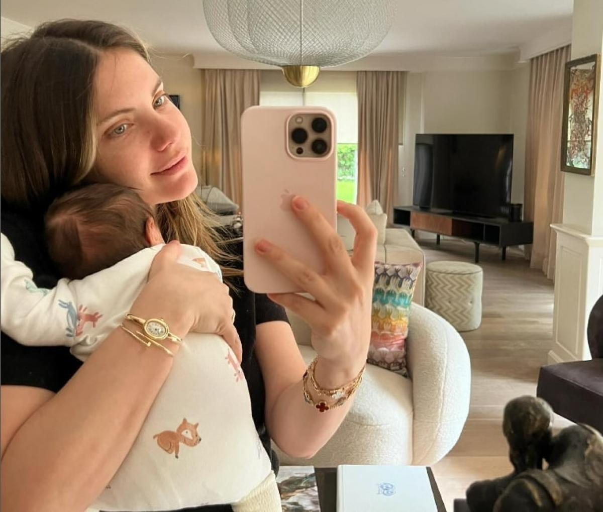 actriță stă în fața oglinzii cu bebelușul în brațe