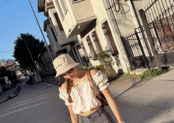 Afra Saracoglu poartă o pălărie și privește în jos