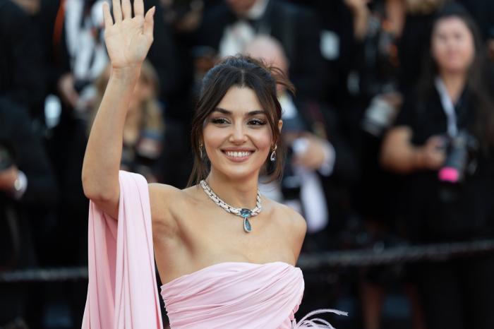 Hande Ercel zâmbește spre fotografi pe un fundal deschis la culoare