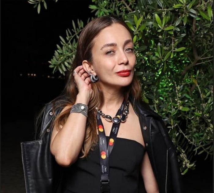 Damla Sonmez poartă părul desprins și își ține mâna dreaptă după ureche