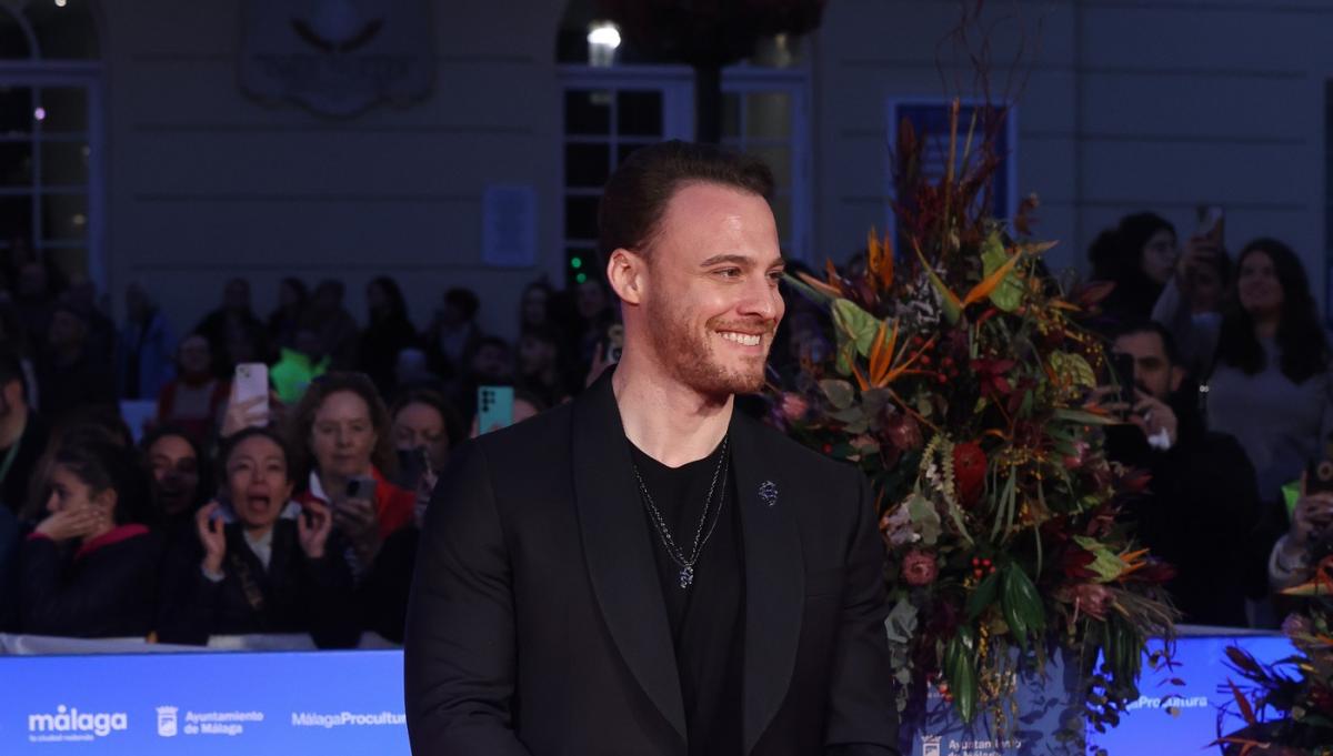 Kerem Bürsin poartă un outfit negru pe un fundal închis la culoare