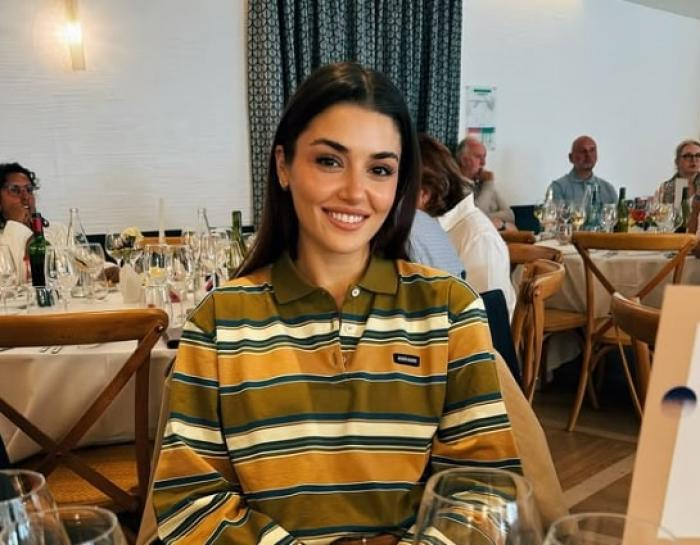 Hande Erçel poartă un top cu mânecă lungă și zâmbește într-un restaurant