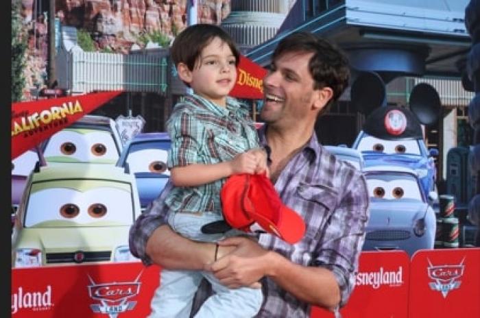 Patricio Borghetti își ține fiul în brațe și zâmbește pe un fundal deschis la culoare