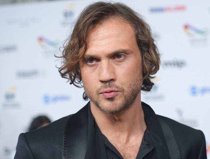 Aras Bulut İynemli poartă părul lung și o bluză neagră