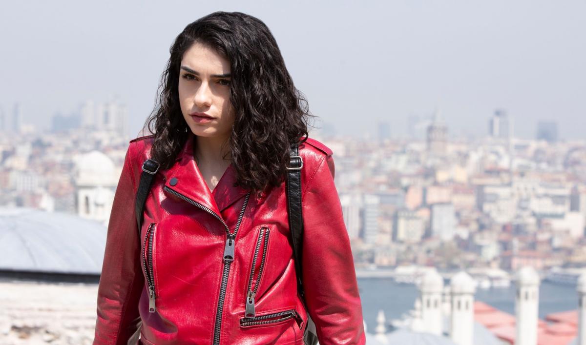 Hazar Erguclu poartă o geacă de blugi roșie și are părul brunet desprins
