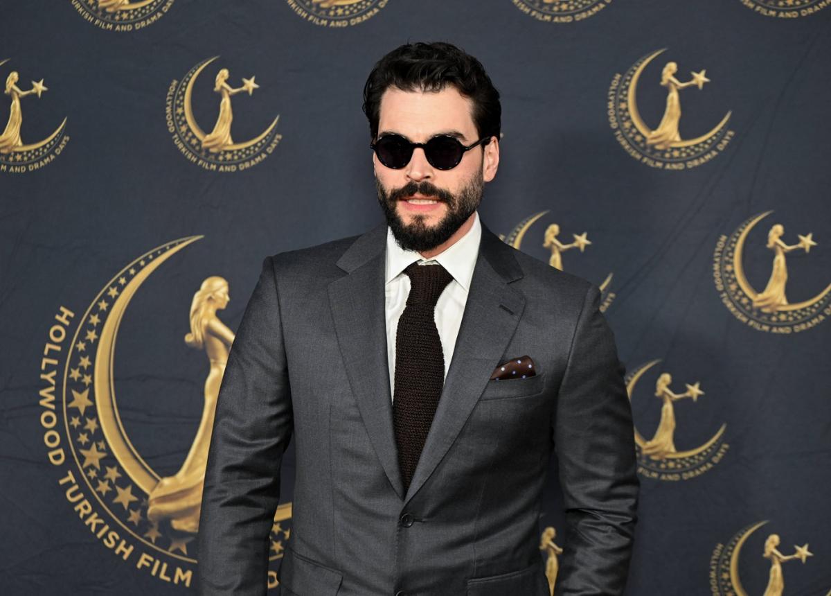 Akin Akinozu poartă costum și cravată și ochelari de soare