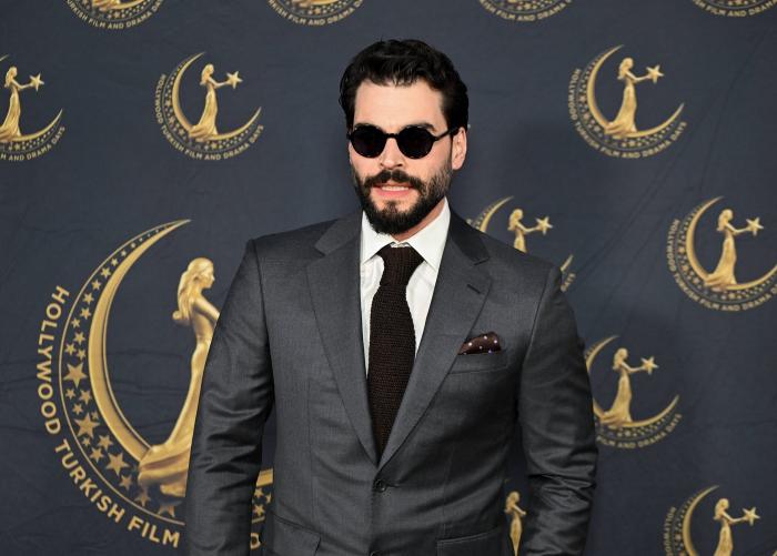 Akin Akinozu poartă costum și cravată și ochelari de soare