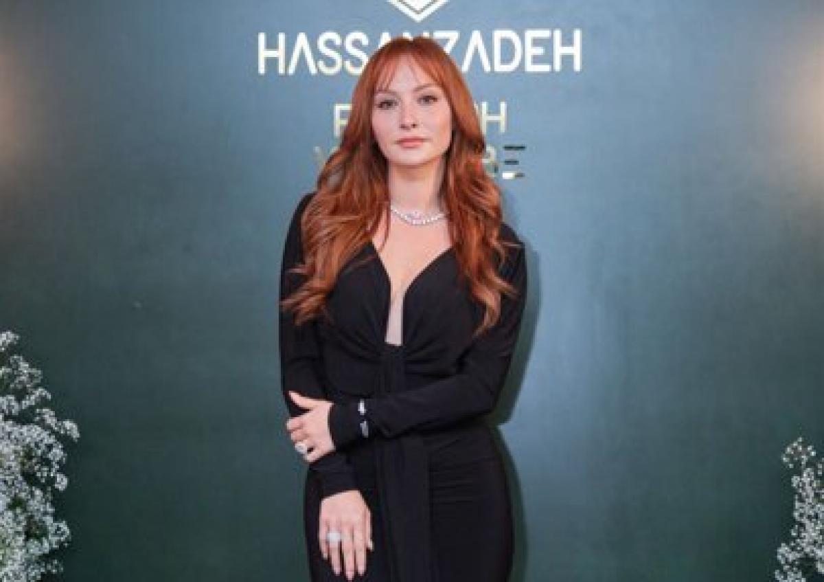 Başak Gümülcinelioğlu poartă o rochie neagră cu mâneci lungi și are părul roșcat