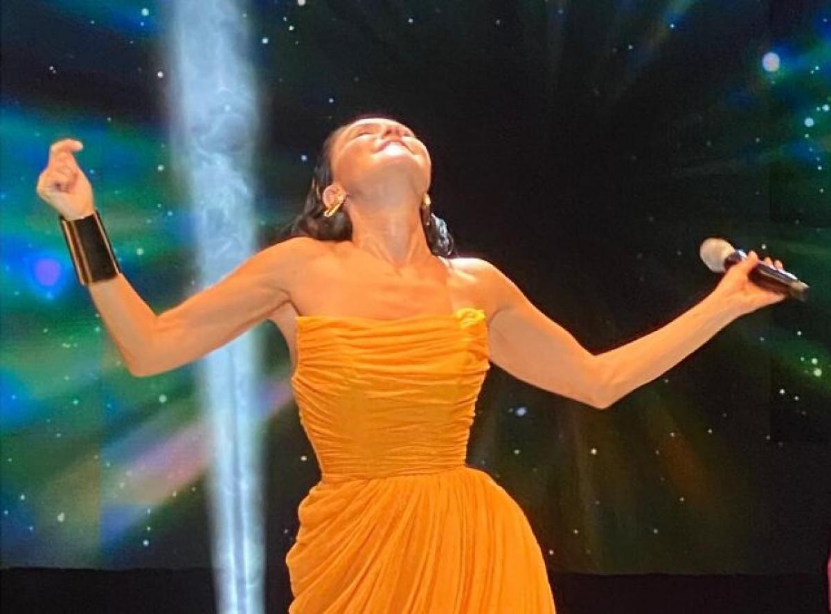 Șevval Sam poartă o rochie fără mâneci și ține mâinile ridicate