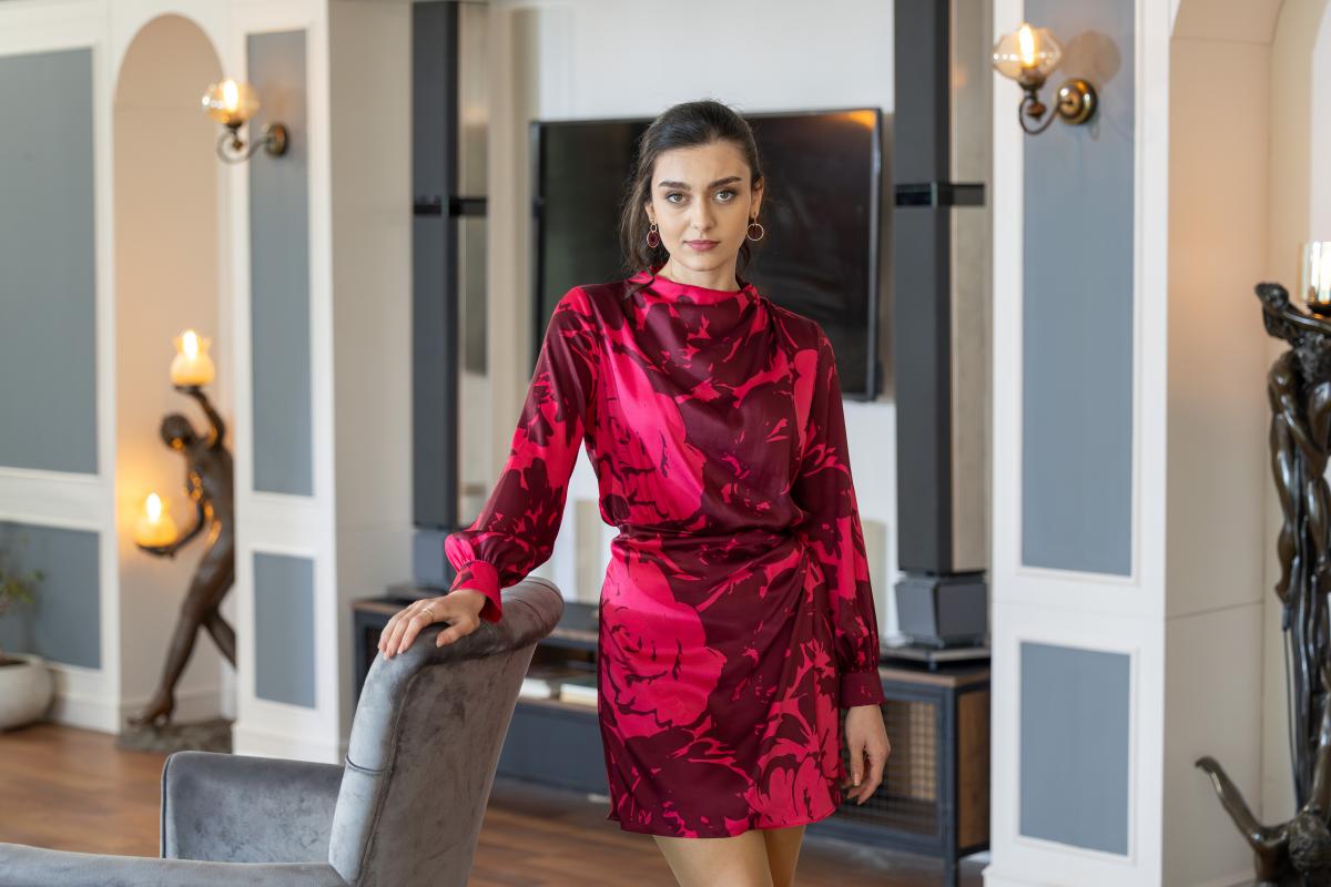 Hilal Tufek poartă o rochie cu mâneci lungi pe un fundal deschis la culoare